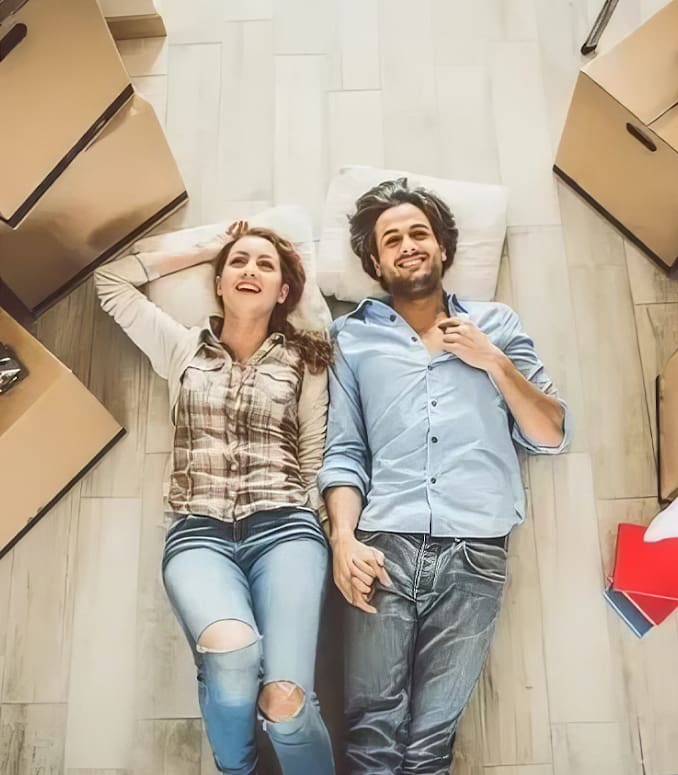 A man and woman laying on the floor in front of boxes.