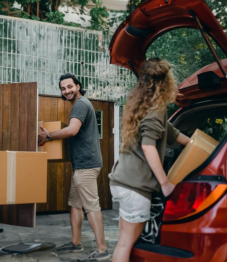 A man and woman loading boxes into the back of their car.