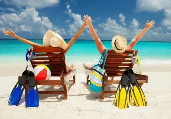 Two people sitting on a beach chair with their arms up.